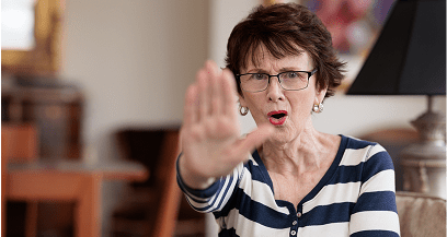 Woman gesturing stop with hand indoors.