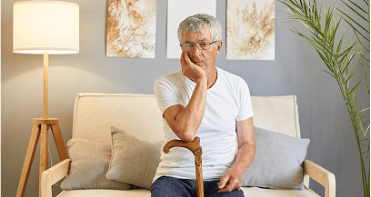 Elderly man sitting with a walking cane.