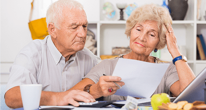 Elderly couple reviewing documents at table.