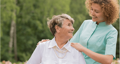 Caregiver comforting elderly woman outdoors smiling.